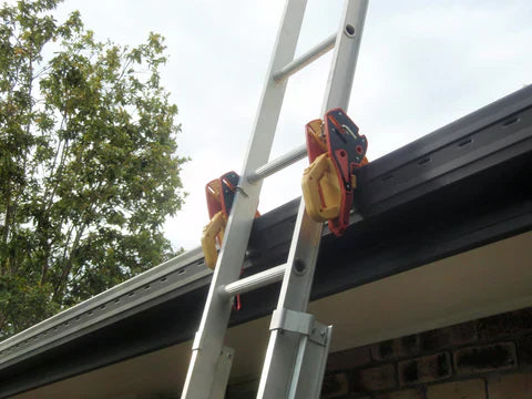 Ladder secured to gutter with Lock Jaw Ladder Grip clamps, safety equipment, outdoor work.