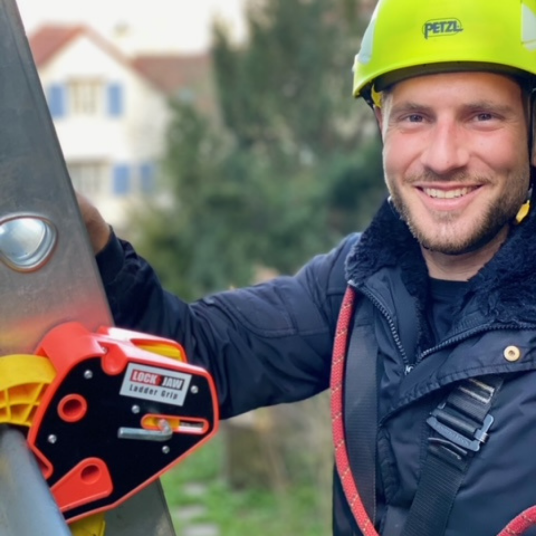 A man accessing wearing safety hat while accessing the roof using and using the best ladder stabilizer in Australia from Lock Jaw Ladder Grip