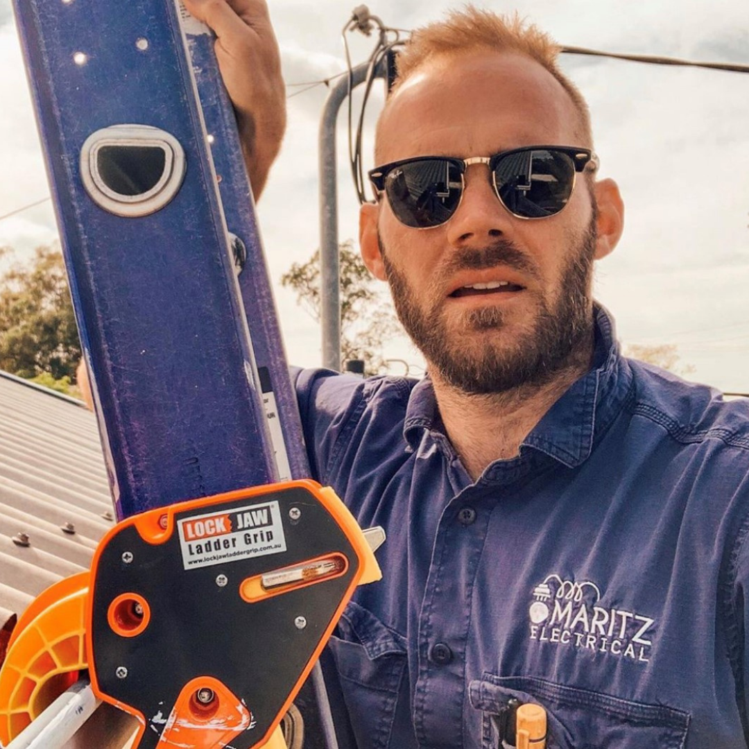 A man wearing a black shades from Maritz Electrical accessing the roof using the best ladder stabilizer in Australia from Lock Jaw Ladder Grip